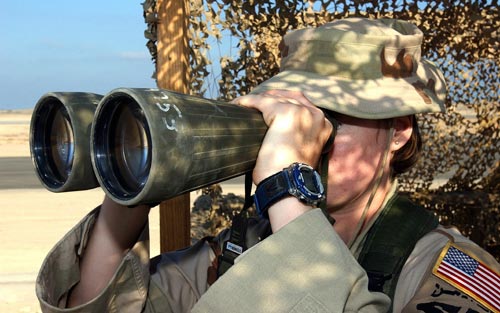 Female soldier looks through binoculars